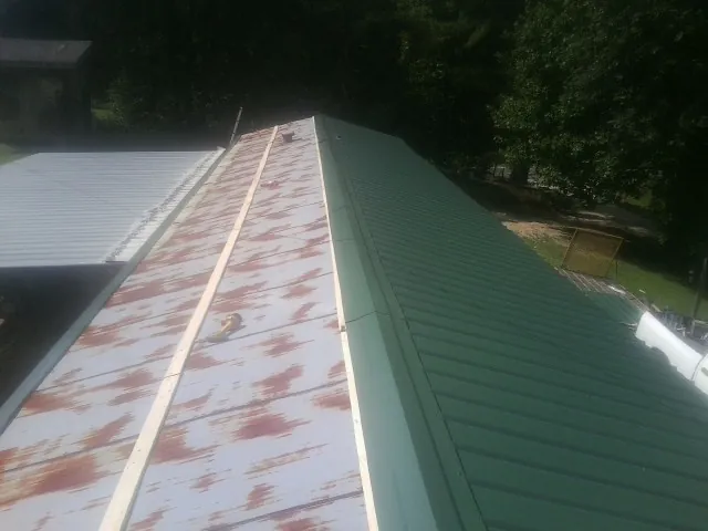 Old rusted panels beside newly installed green metal roofing — Wind Damage Roof Repair by Roofing Brothers in New Freedom