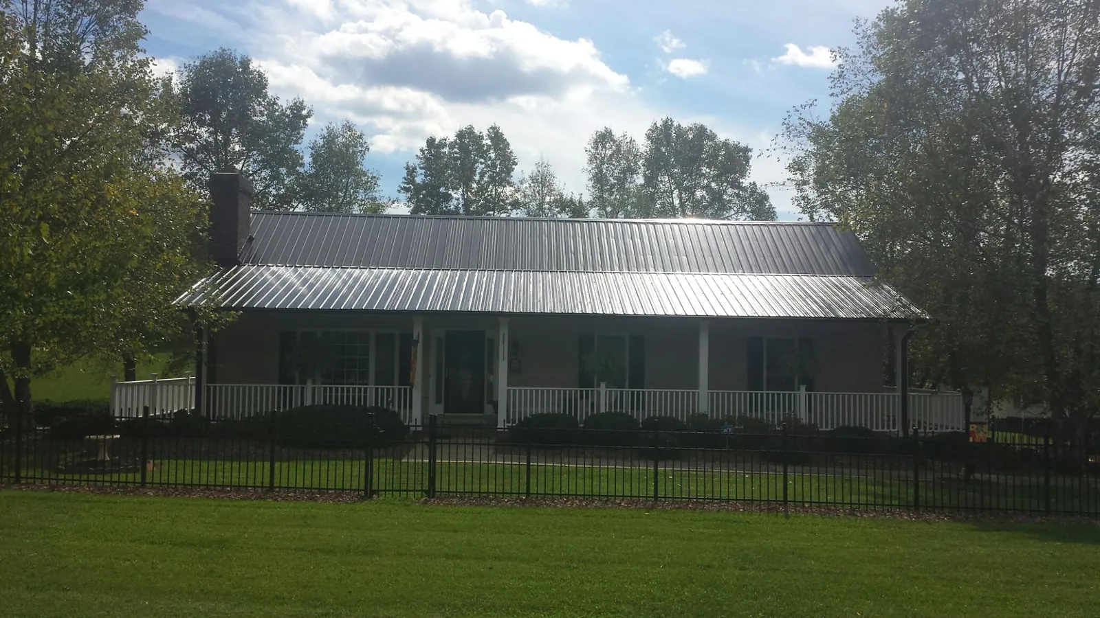 Gray metal roof on a brick ranch with a full width front porch — Gutter Guard Installation work by our crew in New Freedom