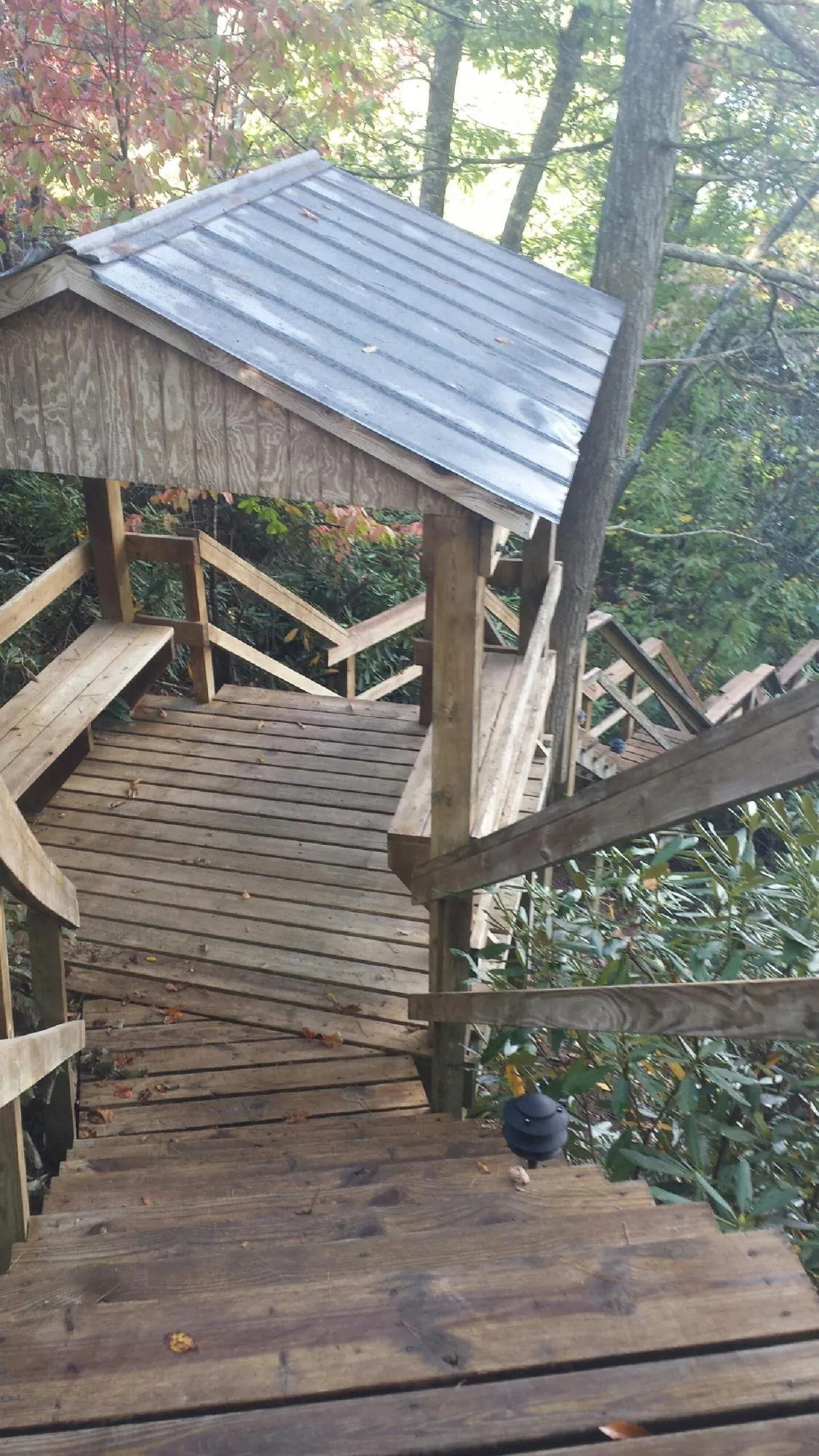 Metal roofed shelter over wooden steps on a wooded walkway — Skylight Repair & Installation work by our crew in New Freedom