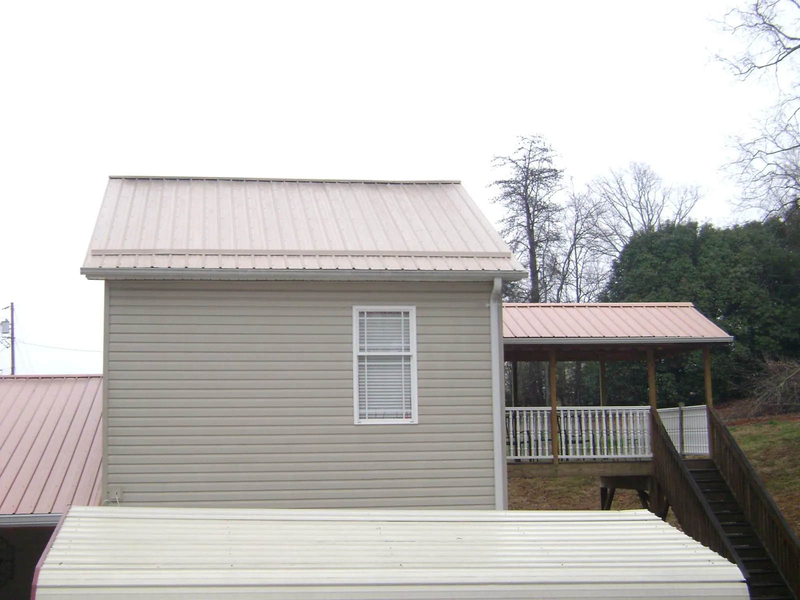 Tan metal roofs on a two story addition and attached porch, from a Roof Replacement job in New Freedom