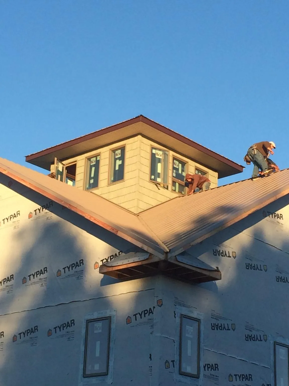 Roofers working around a rooftop cupola on a new metal roof at sunset — Roof Waterproofing in New Freedom by Roofing Brothers